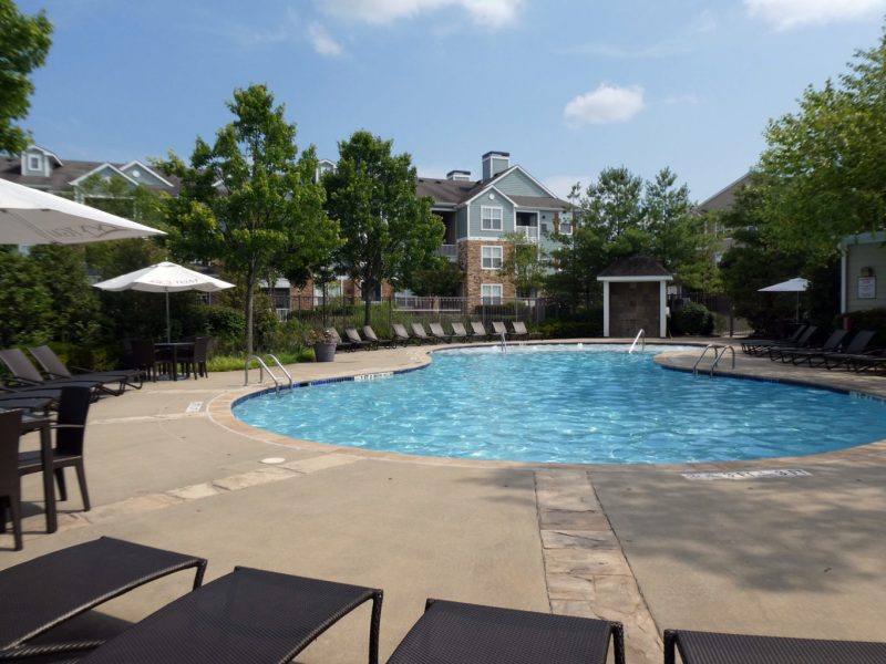 This image shows the resort-style outdoor swimming pool that is offering comfortable beds nearby the pool.