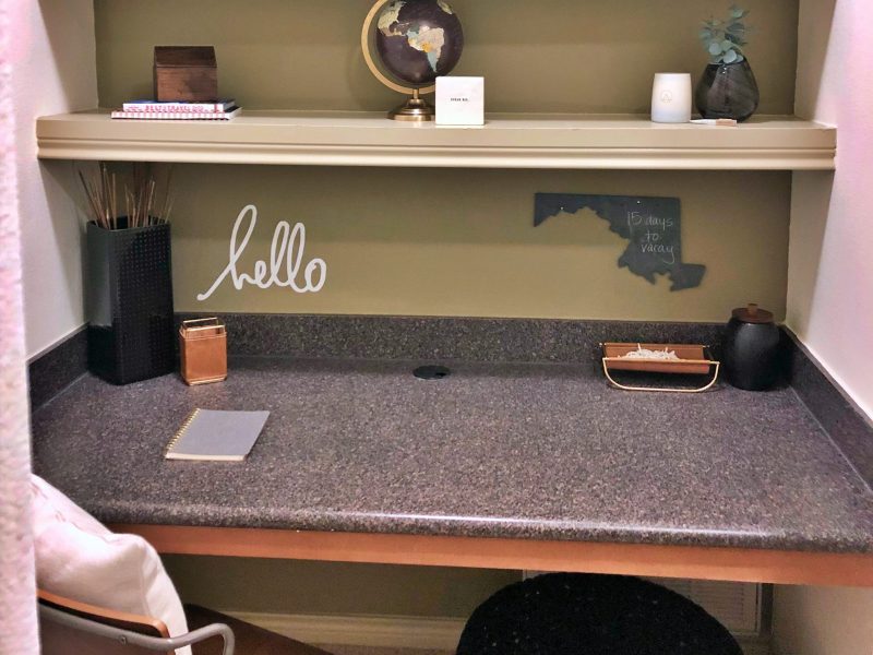 This image shows the Premium Apartment Feature, particularly the working station inside the living room area featuring its light tone wall paint, a desk, and an ideal shelf.